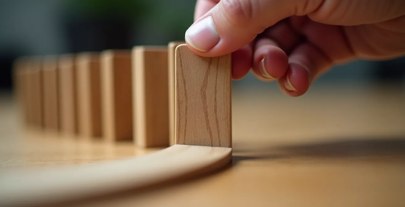 Gros plan sur une main posant délicatement un premier domino dans une chaîne